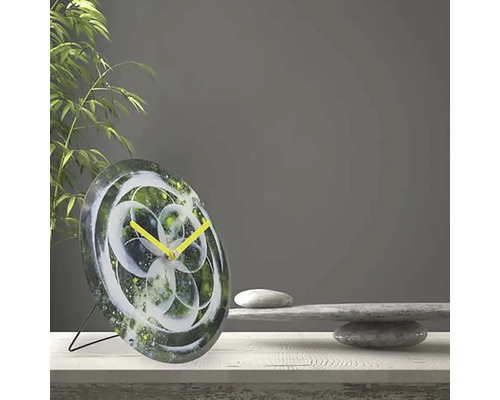 Tischuhr mit abstrakten floralem Muster und gelben Zeigern auf einem Tisch