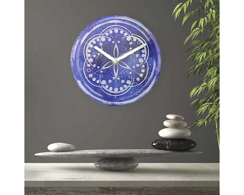 Dekorative Wanduhr mit Mandala-Muster über einem Steinstapel