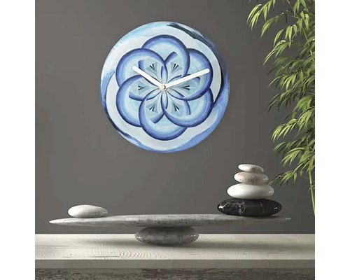 Wanduhr mit blauem Blütenmuster neben Steinbalance