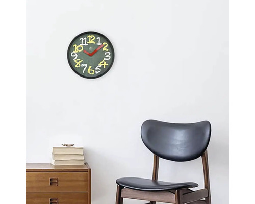 Wanduhr mit Zifferblatt und Zahlen auf einem Holzschrank und einem Stuhl