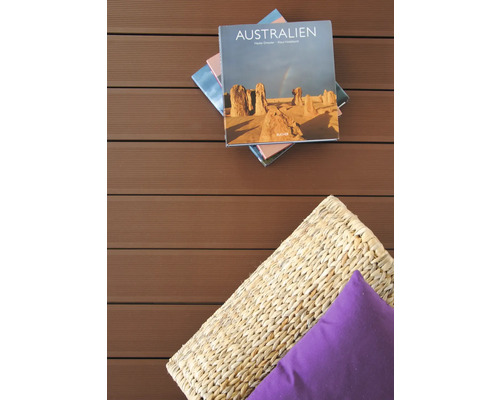 Szene mit Australien-Buch, Korb und Kissen auf einer Holzterrasse