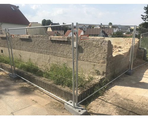 Baustelle mit Bauzaun und beschädigter Mauer