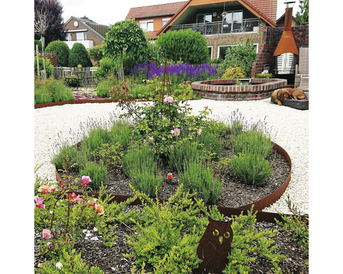 Gestalteter Garten mit Pflanzen, Kieswegen und Dekorationen.