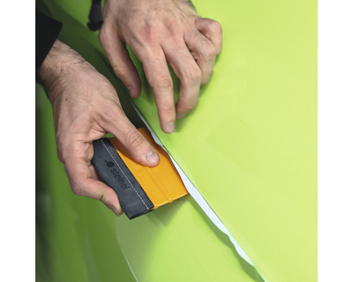 Eine Person verwendet einen Rakel, um eine Folie anzubringen.