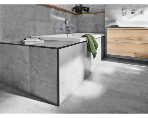 Helles Badezimmer mit Badewanne, Waschtisch und grauen Fliesen.