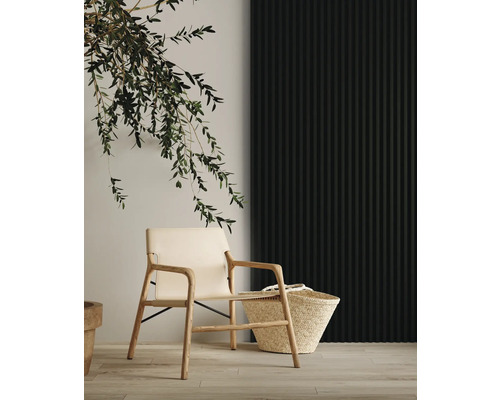 Heller Sessel aus Holz und Korb neben dekorativem Olivenzweig