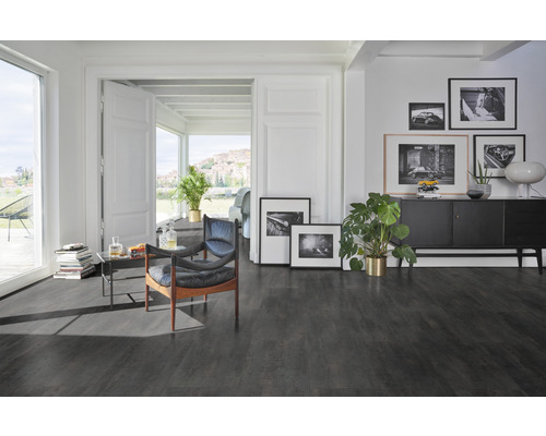 Wohnzimmer mit dunklem Boden, Sessel und Kommode mit Dekoration