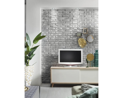 Wohnzimmer mit grauer Ziegelwand, Fernseher und weißem Sideboard