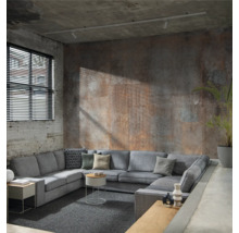 Graues Ecksofa mit Kissen in einem Wohnzimmer mit Backsteinmauer