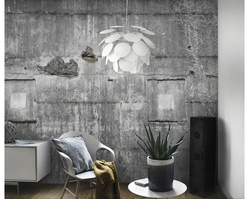 Helles Wohnzimmer mit Betonwand, Stuhl, Kommode, Zimmerpflanze, Lautsprecher und einer runden Pendelleuchte