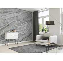Wohnzimmer mit Marmortapete, Sessel, Teppich und Kommode