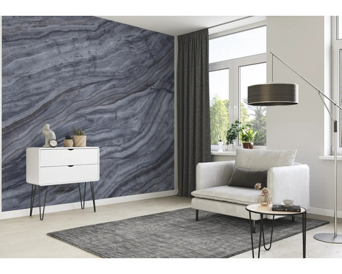 Wohnzimmer mit grauer Marmortapete, weißem Schrank, Sessel und grauem Teppich