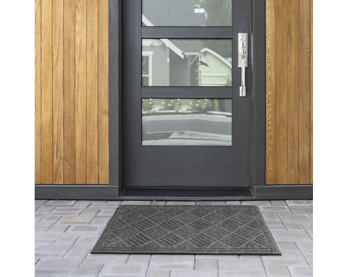 Fußmatte vor einer Haustür mit Glasfenstern und Holzverkleidung