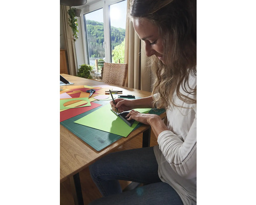 Frau arbeitet mit Papier, Lineal und Stift an einem Tisch.