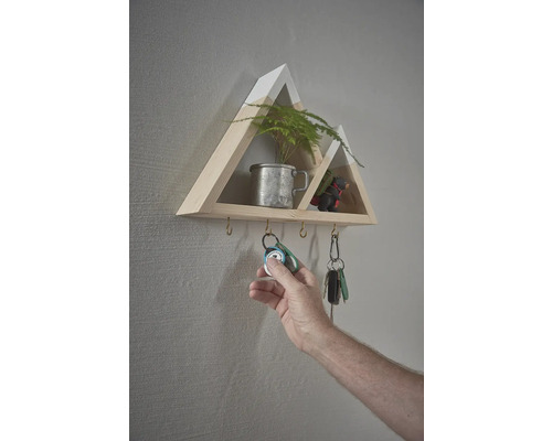 Wandregal in Bergform mit Schlüsselhaken und Hand beim Aufhängen von Schlüsseln