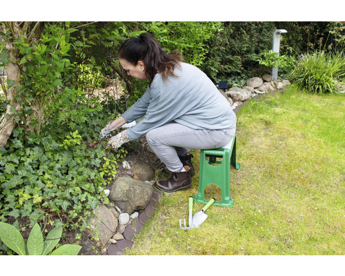 Eine Frau arbeitet im Garten mit einer Gartenbank und Gartengeräten.