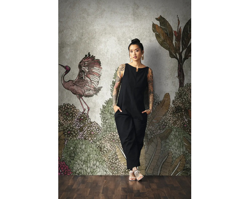 Frau vor einer gemusterten Fototapete mit Pflanzenmotiven