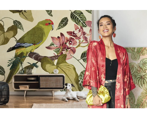 Frau mit rotem Kimono vor einer floralen Fototapete mit Papageien und Orchideen in einem hellen Wohnzimmer