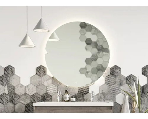Badezimmer mit rundem Spiegel mit Beleuchtung, Waschbecken und sechseckigen Fliesen.