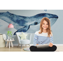 Mädchen mit Tablet vor einer Fototapete mit Wal-Motiv, einem Sessel, einem Beistelltisch und einer Lampe.