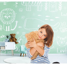 Mädchen umarmt Teddybär vor einer Wand mit Tierzeichnungen im Kinderzimmer.