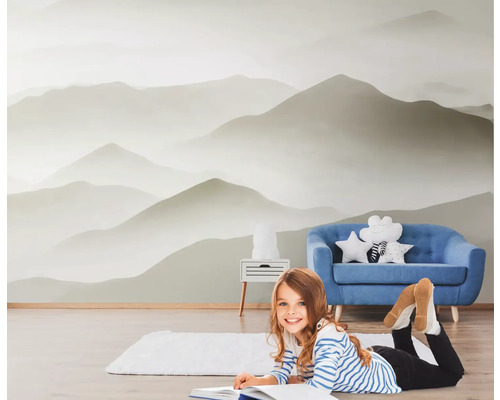 Raum mit Fototapete Berglandschaft, blauem Sofa und lesendem Kind
