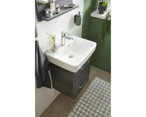 Badezimmerwaschtisch mit Unterschrank, Armatur und Accessoires in einem hellen Raum