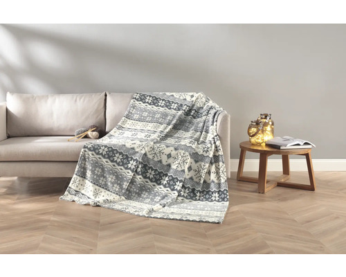 Wohnzimmer-Szene mit Sofa, Wolldecke mit Muster, Beistelltisch mit Buch und Dekoration