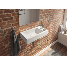 Badezimmer mit weißem Waschbecken an einer Backsteinwand, ergänzt durch einen Spiegel und Armaturen.