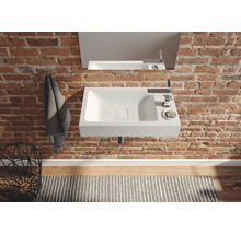 Modernes Badezimmer mit Waschbecken, Armatur und Spiegel an einer Backsteinwand