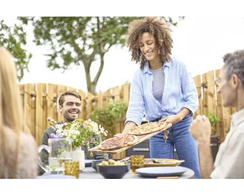 Frau serviert Pizza bei einer Gartenparty.