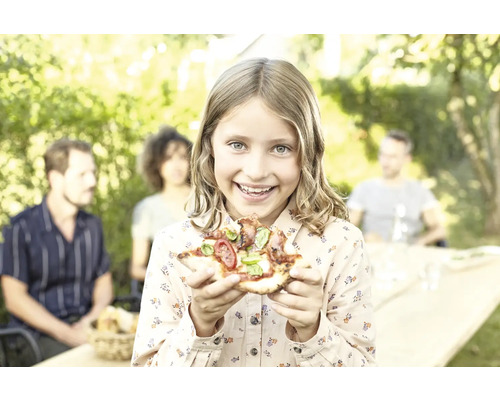 Mädchen hält Pizza im Garten, Familie im Hintergrund