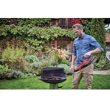 Ein Mann bedient einen Grillanzünder in einem Garten.