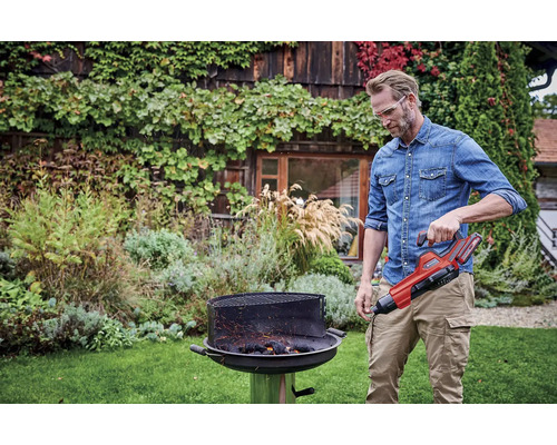 Ein Mann bedient einen Grillanzünder in einem Garten.