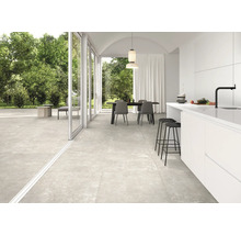 Heller Wohnraum mit Fliesenboden, Esstisch und offener Küche.