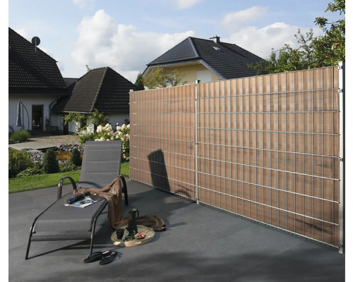 Gartenszene mit Sichtschutzzaun, Liegestuhl und Haus im Hintergrund