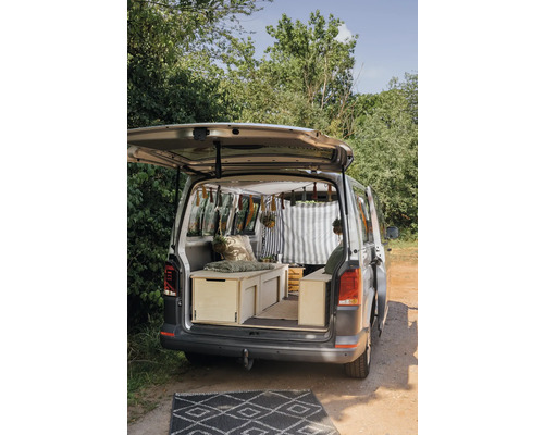 Ausgebauter Kastenwagen mit Holzeinbauten und Teppich vor dem Fahrzeug.