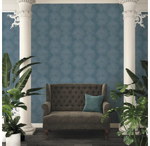 Dekoratives Interieur mit einem Sofa vor einer blauen Tapete mit Kreismuster, flankiert von Säulen und Pflanzen.