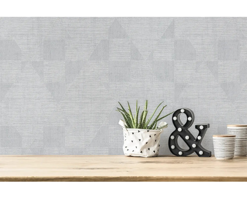 Wand mit geometrischer Mustertapete und Dekoration auf einem Holztisch
