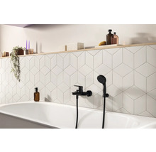 Badezimmer mit Badewanne, schwarzer Armatur und weißen Wandfliesen im geometrischen Design
