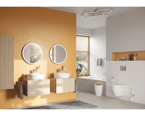 Helles Badezimmer mit Doppelwaschtisch, runden Spiegeln, Badewanne und Toilette.