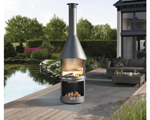 Außenbereichszene mit einem runden Holzkohlegrillkamin auf einer Terrasse mit Sitzgelegenheiten im Hintergrund