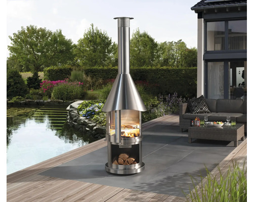 Edelstahl-Außenkamin mit Holz und Grill auf Terrasse mit Gartenteich
