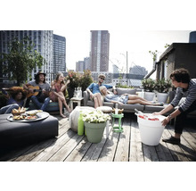 Gruppe von Menschen entspannt auf einer Dachterrasse mit Möbeln und Pflanzenkübeln.