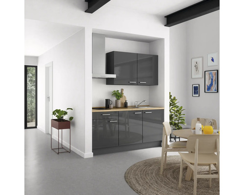 Graue Küchenzeile mit Hängeschränken, Dunstabzugshaube und Esstisch in hellem Raum