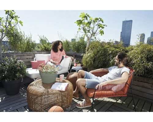 Ein sonniger Dachgarten mit Sitzgelegenheiten, Pflanzen und zwei Personen.