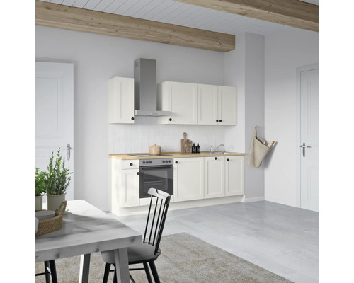 Helle Küche mit weißen Schränken, Dunstabzugshaube und Holzarbeitsplatte in einem hellen Raum.