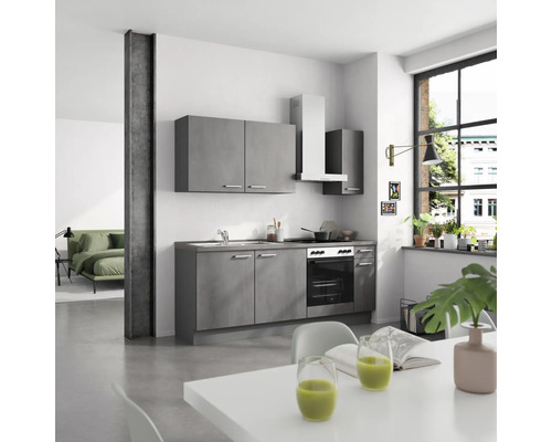 Küche mit Küchenschränken, Spüle, Herd, Dunstabzugshaube und Esstisch in einem hellen Raum.