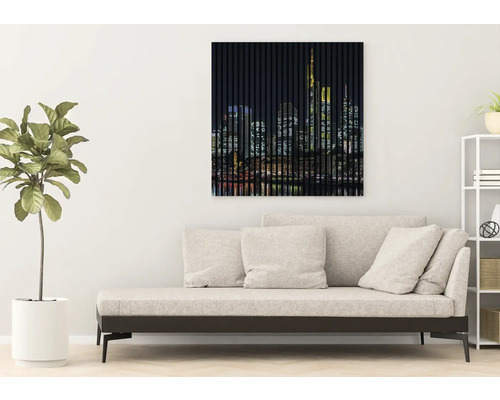 Wandbild mit Skyline-Motiv über einer Couch in einem Wohnzimmer.