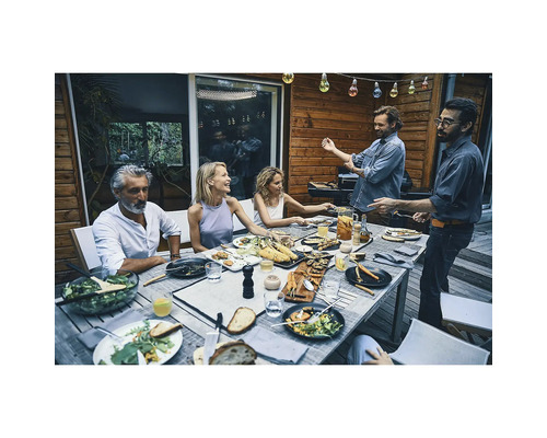 Gesellschaft beim Grillen im Freien mit zubereiteten Speisen auf dem Tisch